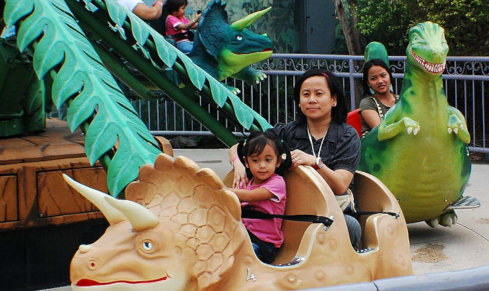 A charming scene from 2008, featuring several happy Filipino kids and their mothers (or aunties) riding a Dinosaur merry-go ride. Each child, and co-pilot, has their own 'Dinosaur' car, such as a Triceratops or Tyrannosaurus. Original image - 'Enchanted Kingdom DinoSoarUs ride' - by ewol, c/o Wikimedia Commons. Used and adapted under the terms of the Creative Commons Attribution-Share Alike 3.0 Unported license.
